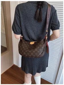 Detail of dark brown dumpling bag with monogram pattern and wide fabric strap