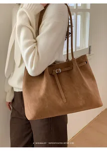 Detail showing brown faux suede texture and silver metal buckle on the tote bag