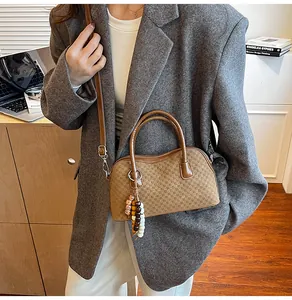 Close-up of brown checkered pattern handbag with beaded charm worn by a model in office