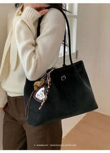 Detail of black matte tote bag with leopard print heart mirror charm and buckled strap