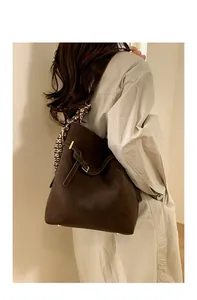 Detail of dark brown suede bucket bag with decorative scarf and golden metal hardware