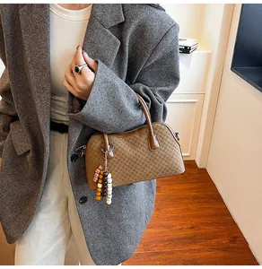 Gros plan du sac baguette marron en cuir gaufré avec accessoire de breloque en perles