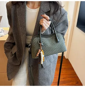 Détail du sac baguette tissé vert foncé avec breloque en perles de bois et poignée chic