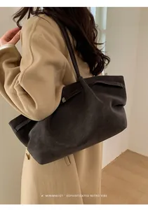 Detalle de un bolso tote de ante gris oscuro combinado con un abrigo de lana beige casual