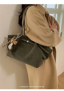 Detalle de bolso tote de ante verde oliva con colgante de corazón de leopardo y metal