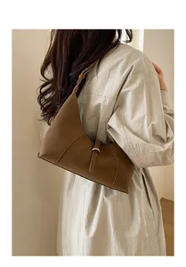 Dark brown minimalist faux suede dumpling bag shown from a stylish side view on a model