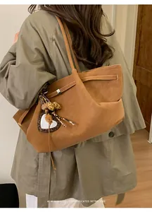 Bolso tote marrón con colgante de corazón de leopardo mostrado en modelo con gabardina