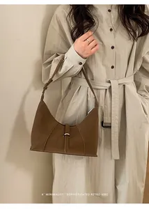 Close-up of minimalist brown leather bag with vertical stitching and silver buckle detail