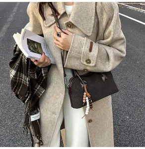 Gros plan sur un sac baguette tressé marron foncé avec pompon ethnique et perles