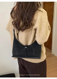 Rear view of minimalist black suede hobo bag on model wearing a knit sweater