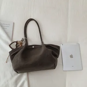 Detalle del bolso tote de ante marrón oscuro con colgante de corazón de leopardo en tela