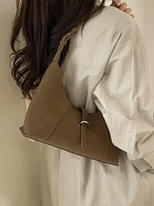 Brown leather crescent shoulder bag with metallic buckle detail on model