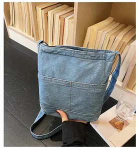 Détail du sac seau en jean bleu avec surpiqûres contrastées et poches avant pratiques