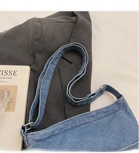 Détail de la texture en denim foncé et de la large bandoulière réglable du sac chic