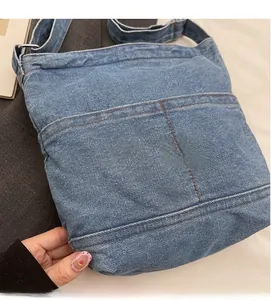 Détail du sac fourre-tout en jean bleu avec coutures orange et boucle en métal réglable