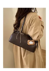 Detailed view of brown leather shoulder bag with drawstring and cute bear charm
