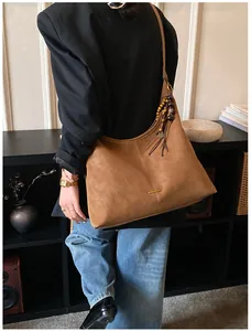 Dettaglio borsa tote in pelle scamosciata marrone con nappa di perline decorativa