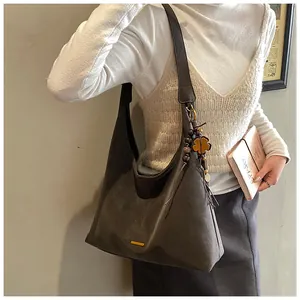 Dettaglio della borsa tote in pelle scamosciata marrone con finiture dorate e nappa