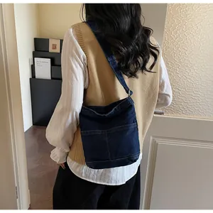 Détail d'un sac cabas en denim bleu foncé avec coutures apparentes et bandoulière large