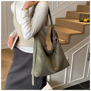 Dettaglio borsa tote grigio-verde con trama opaca e ciondolo decorativo con nappine e perline