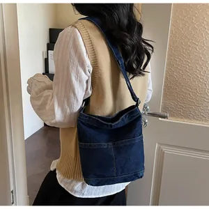Détail d'un sac seau en jean bleu foncé avec des poches plaquées sur le devant
