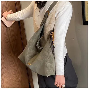Dettaglio della borsa tote verde oliva con texture scamosciata e nappa con perle di legno