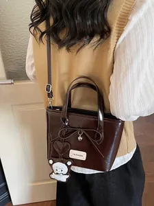 Deep brown bucket bag with a bow and heart charm shown on a model from a side-rear view