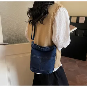 Vue détaillée du sac seau en denim montrant les coutures jaunes et poches frontales