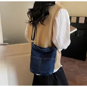 Détail du sac bandoulière en denim bleu foncé avec coutures contrastées et poches externes