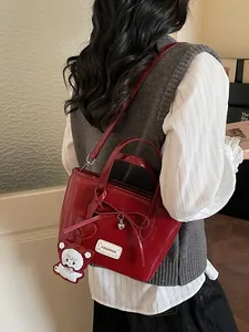 Red glossy bucket bag with bow detail and bear charm in a minimalist fashion style