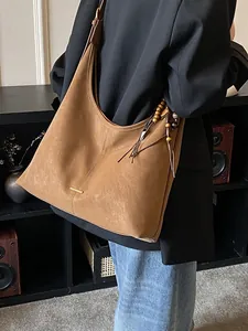 Borsa hobo marrone in finta pelle scamosciata con nappa di perline su una modella