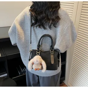 Detail of woven texture black baguette bag with cute white plush bunny charm