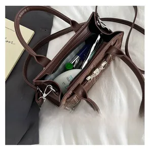 Capacità interna della borsa in pelle marrone scuro con vari oggetti personali essenziali