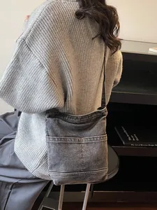 Sac seau en denim gris foncé avec plusieurs poches porté par le mannequin