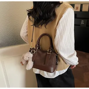 Detail of dark brown woven Boston bag with a cute plush rabbit charm and gold hardware