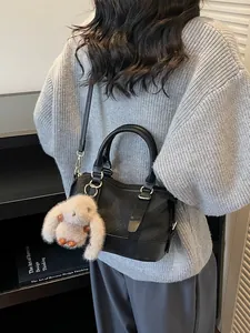 Minimalist black woven baguette bag with plush bunny charm and crossbody strap