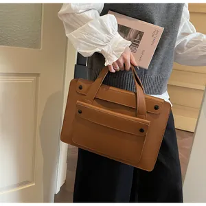 Close-up of brown waterproof tote bag showing textured PU leather and flap pocket details