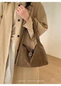 Detail of vintage brown suede tote bag with silver buckle worn on a beige coat