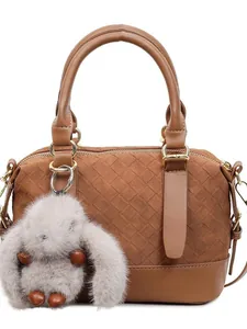 Brown woven baguette bag with a plush bunny charm and golden hardware on white background