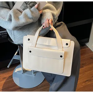 Detailed view of cream leather tote bag with four black snap buttons and sturdy handles