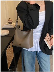 Détail de la texture cuir grainé et plaque dorée sur un sac seau marron élégant