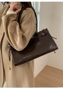 Détail du sac cabas vintage marron en cuir brillant avec boucle dorée en métal E