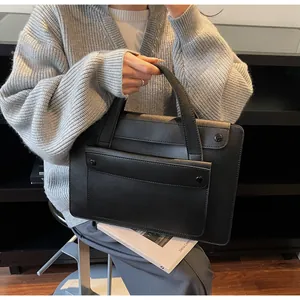 Detailed view of black leather tote bag with front flap pocket in modern office setting