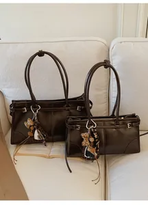 Vue détaillée de cabas en cuir marron foncé avec charms miroir cœur sur un canapé