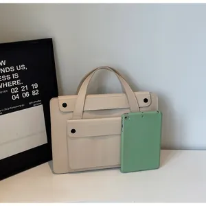 Detail of minimalist cream leather tote bag with front pocket and round button closure