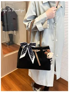 Detail of black tote bag with silk scarf accent and plush bear charm on side