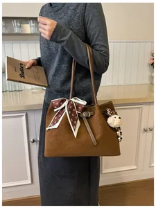 Detail of dark brown suede tote bag with floral scarf and cute plush bear charm accessory