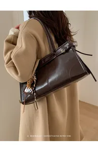 Détail du sac cabas en cuir marron foncé avec boucle métallique en E et fines bandoulières