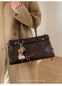 Détail du cabas vintage marron foncé avec texture brillante et charm coeur léopard