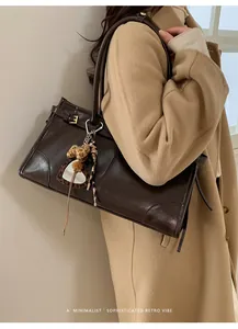 Détail du cabas en cuir marron foncé avec charme léopard en cœur et boucle en métal